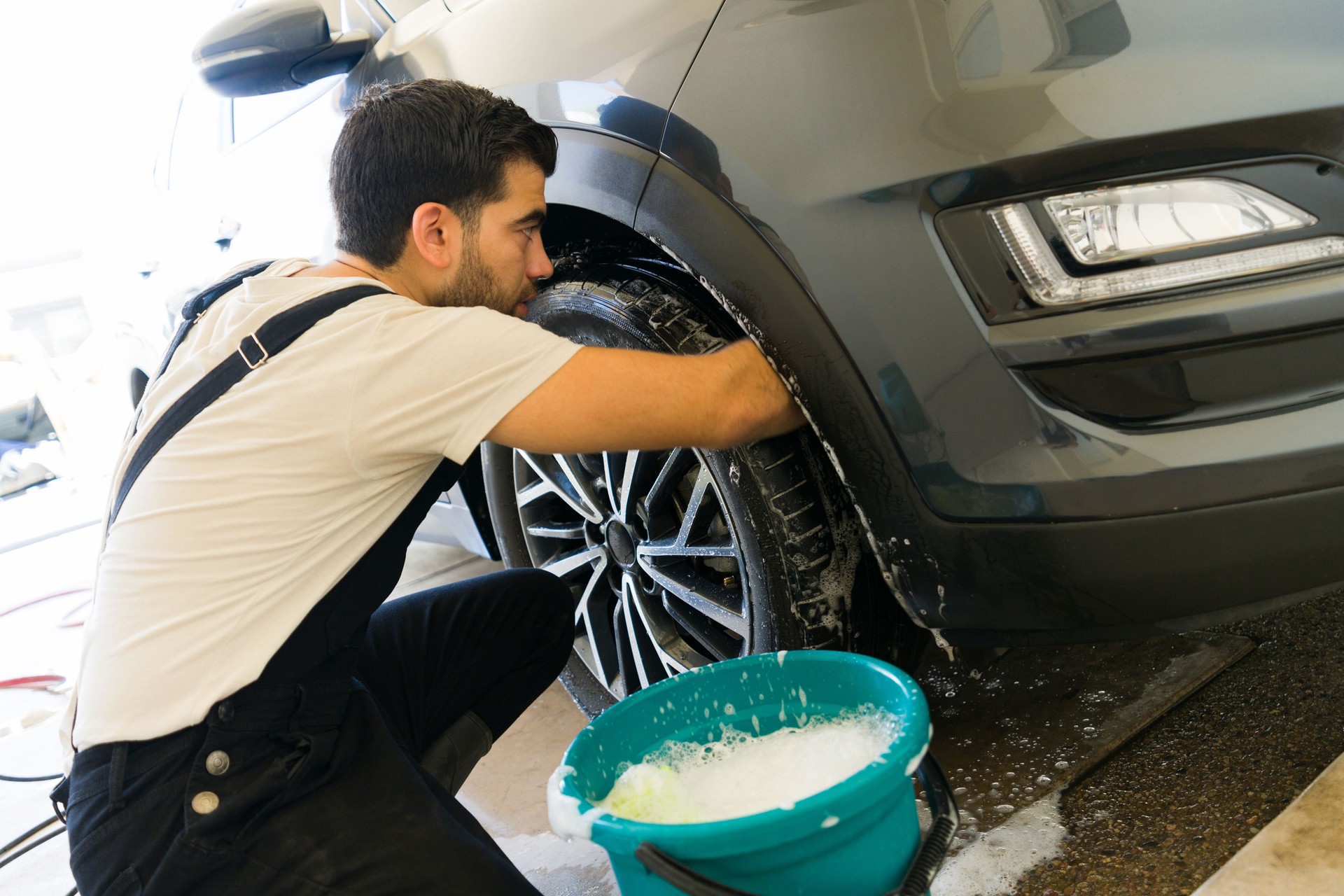 Worker cleaning the undercarriage of a vehicle at a car wash